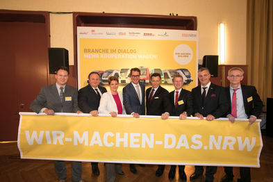 Die Geschäftsführer der nordrhein-westfälischen Eisenbahnverkehrsunternehmen halten ein gelbes Banner hoch, auf dem in weißer Schrift steht: wir-machen-das.nrw