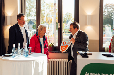 Minister Oliver Krischer überreicht die Wanderbahnhof-Plakette.