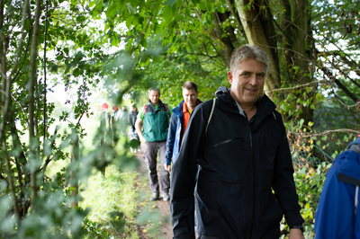 Ein paar Wanderer laufen hintereinander auf einem Waldpfad bei Overath.