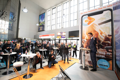 NRW-Verkehrsminister Hendrik Wüst steht an einem Rednerpult, vor ihm stehen viele Pendler und Pressevertreter im Düsseldorfer Hauptbahnhof.