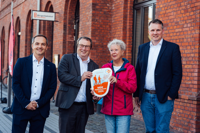 Gruppenbild vor dem Bahnhofsgebäude mit der Plakette.